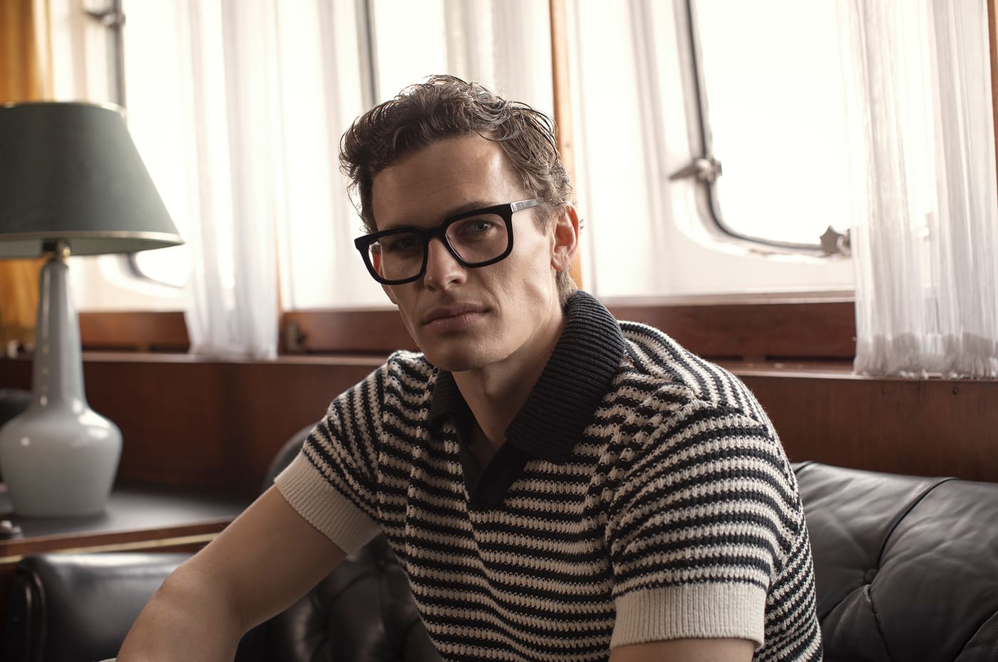 Mann mit kräftiger Acetatbrille in warmem Interieur